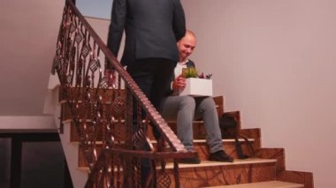 Kovulmuş işadamı merdivenlerde oturuyor.