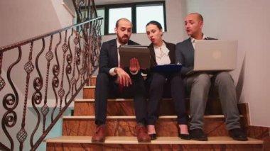 İş ortakları merdivenlerde oturup finans projesi planlıyorlar