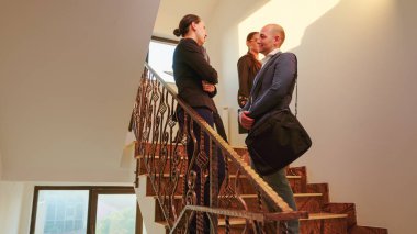 İş ortakları merdivenlerde dikilip konuşuyorlar.