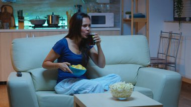 Kanepede oturup televizyon izleyen bir kadın.