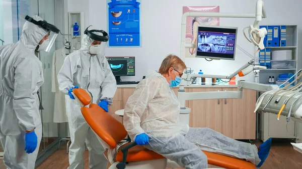 Медсестра в защитном костюме приглашает следующего пациента в стоматологическую палату — стоковое фото