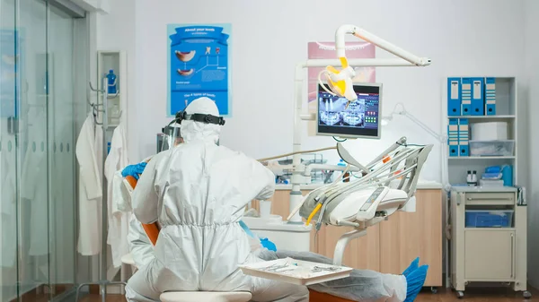 Tandarts en assistent in coverall onderzoeken mond van de patiënt — Stockfoto