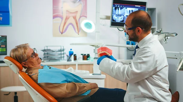 Doctor uitleggen met behulp van mock-up van skelet van tanden — Stockfoto