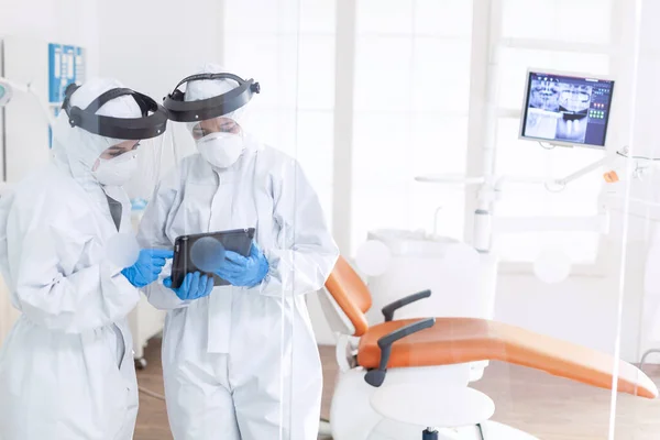 Стоматолог и медсестра во время эпидемии ковида-19 в костюме ppe — стоковое фото