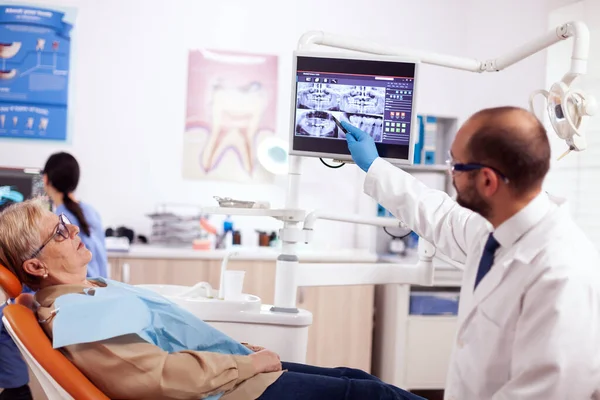 Стоматолог объясняет диагноз пожилой женщине — стоковое фото