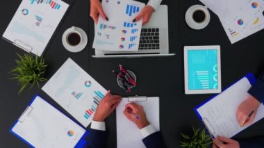 İş arkadaşları büro masasında oturup mali belgeleri tartışıyor.