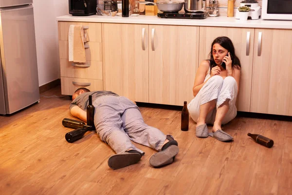 Abused wife using phone for asking help sitting on the floor Stock Image