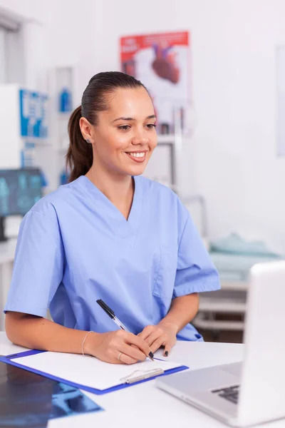 Sourire infirmière médicale écrivant des notes — Photo