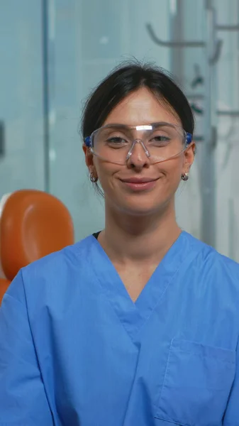 Enfermera sonriendo a la cámara sentada en el consultorio dental — Foto de Stock