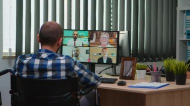 Tekerlekli sandalyedeki engelli yönetici görüntülü konuşma sırasında konuşuyor