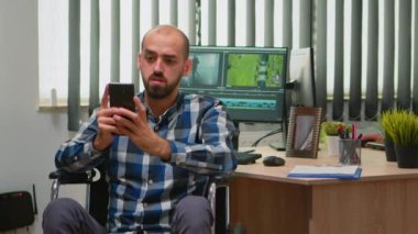 Tekerlekli sandalyedeki video düzenleyici akıllı telefondan mesaj atıyor