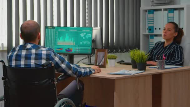 Ondernemer in een rolstoel die financiële statistieken analyseert — Stockvideo