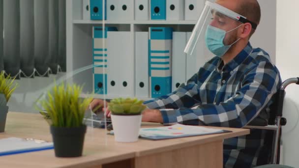 Hombre de negocios discapacitado con protección facial que trabaja en la computadora — Vídeos de Stock