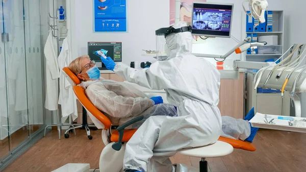 Помощник стоматолога в измерении температуры пациента в костюме — стоковое фото