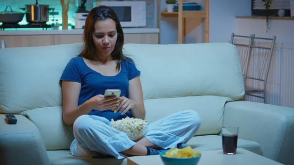 Mujer desplazándose en el teléfono comiendo palomitas de maíz — Foto de Stock