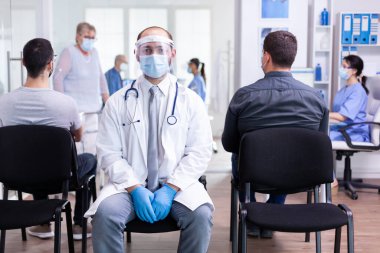 Yüz maskesi ve güneşliği olan yorgun bir doktorun portresi