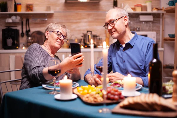 Vecchia coppia utilizzando i telefoni in cucina — Foto Stock