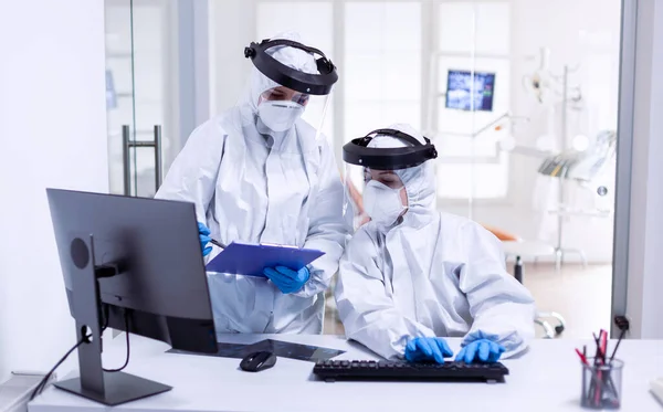 Стоматолог и медсестра во время глобальной вспышки в защитном костюме — стоковое фото