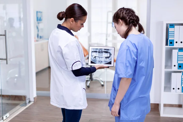Médico dentista y enfermera mirando rayos X digitales — Foto de Stock