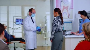 Dişçi doktor, kadını sorguluyor. Not alıyor.