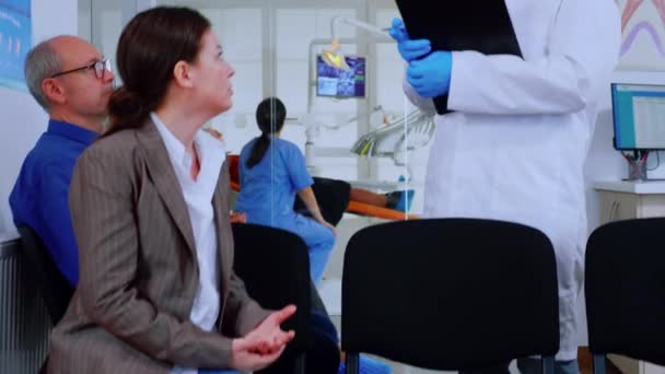 医者は患者の歯の問題についてクリップボードにメモを取る — ストック動画