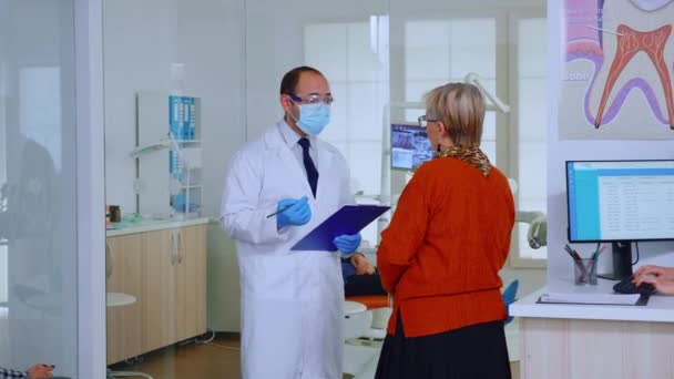 Orthodontiste avec masque parlant avec une femme âgée dans une salle d'attente — Video