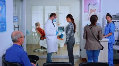 Diş hekimi tablet kullanan hastaya diş röntgeni gösteriyor.