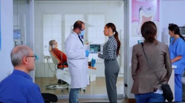 Hastaya diş röntgenini açıklayan tablet kullanan ortodontist