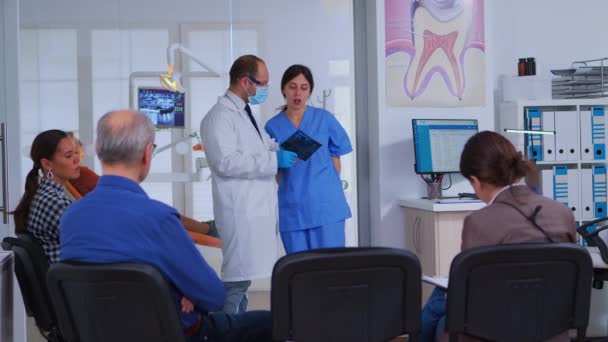Lekarz rozmawia z asystentką trzymającą prześwietlenie zębów — Wideo stockowe