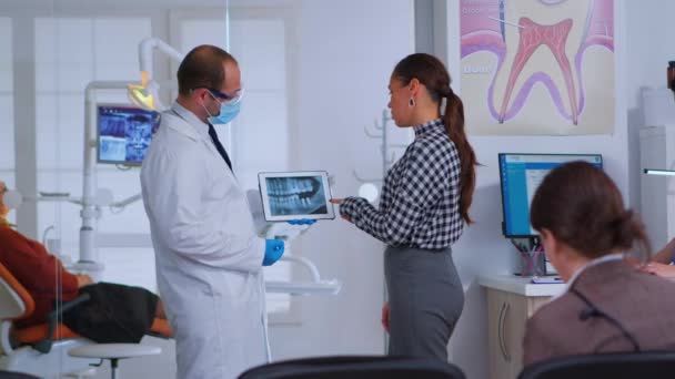 Dentista en sala de espera hablando con paciente mujer sobre rayos X — Vídeos de Stock