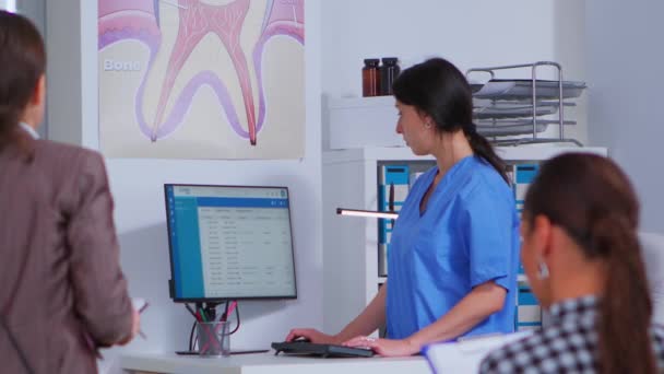 Assistente dentale prendere appuntamenti mentre la donna chiede aiuto — Video Stock