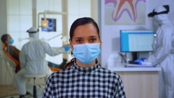 Portret van vrouw met masker in tandheelkundig kantoor op zoek naar camera — Stockvideo