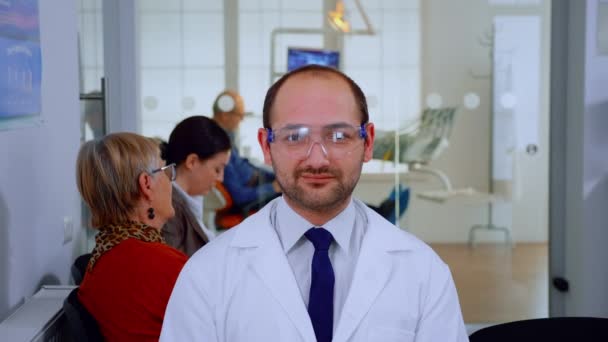 Ritratto di stomatologo che sorride alla telecamera mentre si trova nello studio dentistico — Video Stock