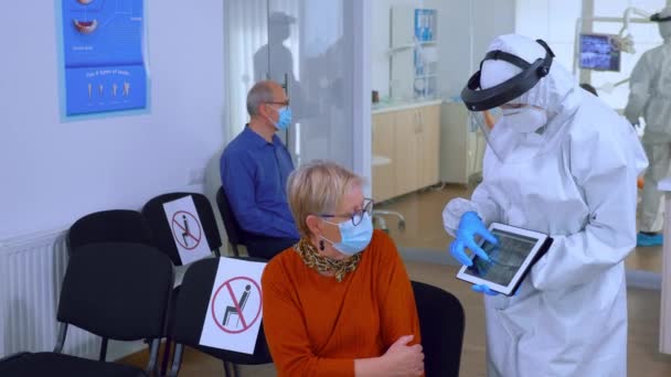 Médecin dentiste avec écran facial pointant sur l'écran du comprimé — Video