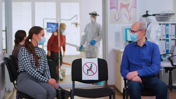 Menschen mit Masken diskutieren auf Stühlen und halten Abstand — Stockvideo