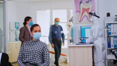 Maskeli kadın resepsiyonda sandalyede oturuyor.