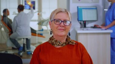 Doktor hastayı muayene ederken yaşlı kadın kameraya bakıyor.