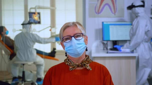 Portrait of retired patient with mask in dental office looking on camera — Stock Video