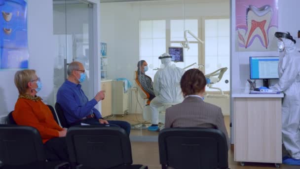 Les patients avec des masques de protection wating médecin en clinique dentaire — Video