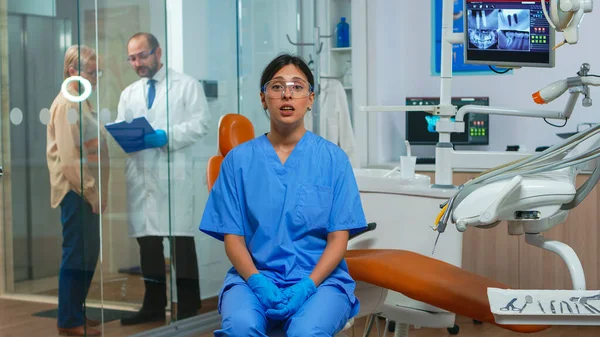 牙医助理看着与病人交谈的相机 — 图库照片
