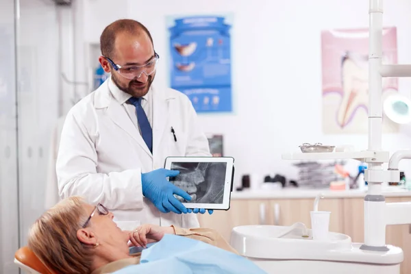 Стоматолог в форме объяснения диагностики во время консультации — стоковое фото