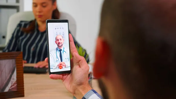 Geschäftsmann telefoniert während der Arbeitszeit per Video mit Arzt — Stockfoto