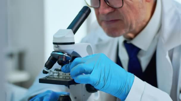 Ηλικιωμένος στο εργαστήριο κάνοντας έρευνα χρησιμοποιώντας μικροσκόπιο — Αρχείο Βίντεο