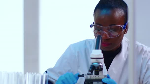 Primer plano de la científica negra que investiga con microscopio — Vídeos de Stock