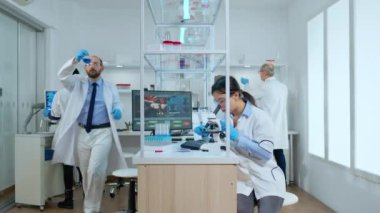 Kimyager doktor tüp testinden sıvı kontrolü yapıyor. Bilim adamı hemşireyle konuşuyor.