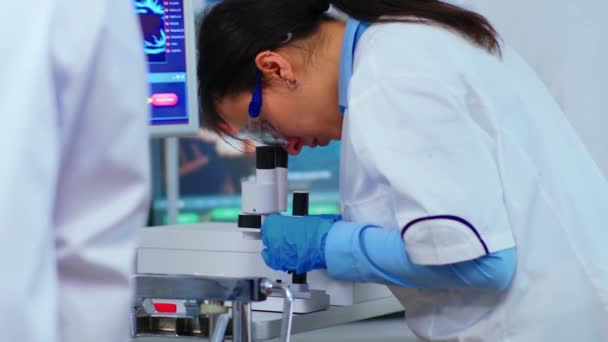 Forskargrupp för biokemisk forskning som arbetar med mikroskop — Stockvideo
