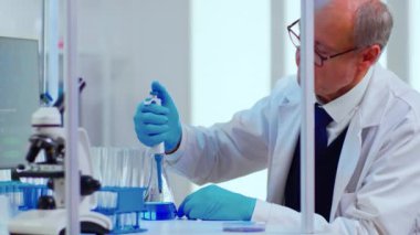 Laboratuvar kıdemli bilim adamı test tüpleri ve pipetle çalışıyor.