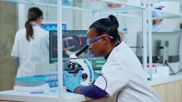 Cientista mulher africana usando microscópio no laboratório moderno — Vídeo de Stock