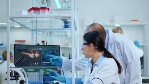 Cientistas de pesquisa trabalhando em computadores com equipamentos médicos — Vídeo de Stock