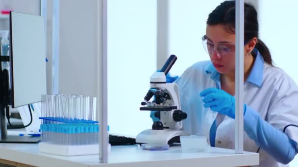 Wissenschaftler platziert ein Dia auf der Probenbühne eines Labormikroskops — Stockvideo